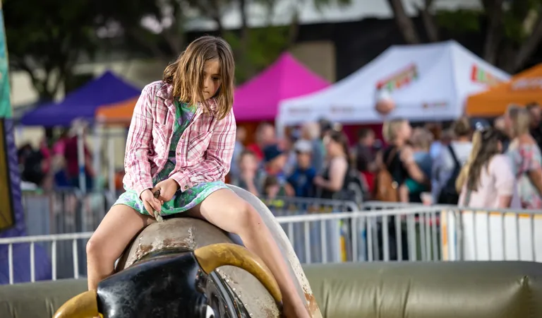 A child riding a mechanical bull at the free kids area, One Long Table