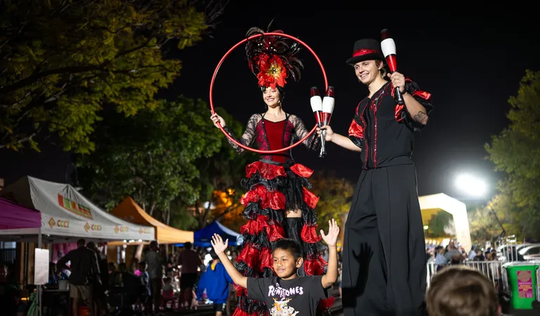 Costumed stilt entertainers performing above the crowd after dark